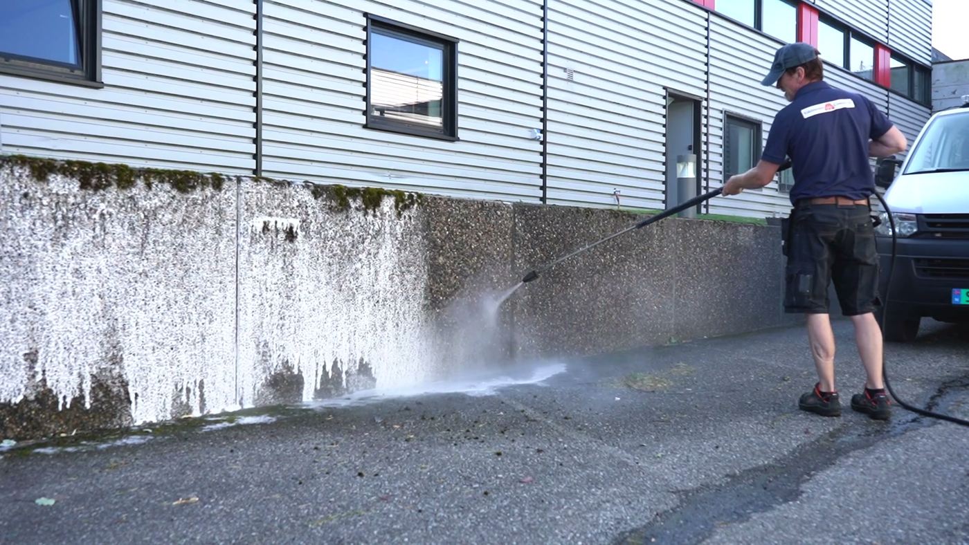 VMC-medarbeider rengjør en betongmur med høytrykk