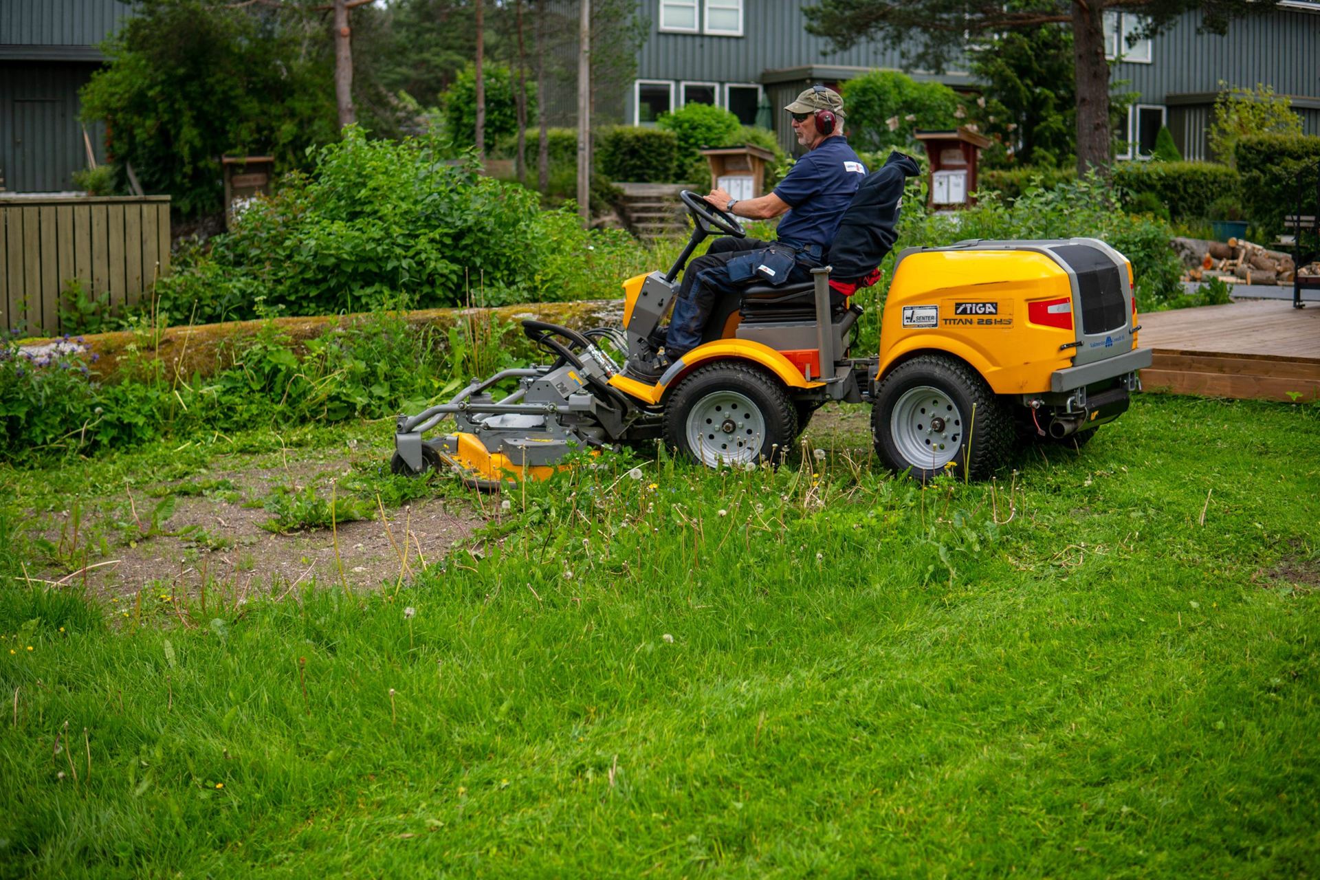 VMC-medarbeider klipper plenen ved et boligbygg